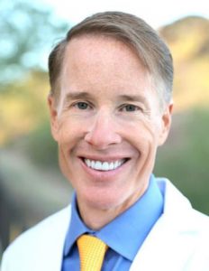 Photo of Dr. Christianson in a white coat, blue shirt, and gold tie