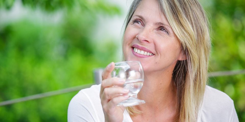 Woman drinks a glass of water outside