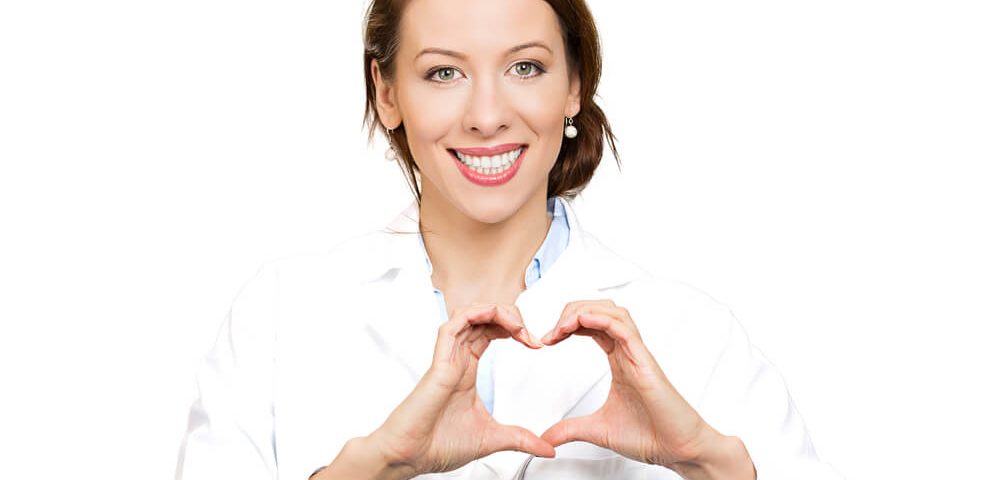 A doctor in a white lab coat making a heart symbol.