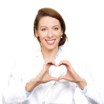 A doctor in a white lab coat making a heart symbol.