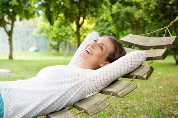 Portrait,Of,A,Smiling,Older,Woman,Relaxing,On,Hammock,Outdoors